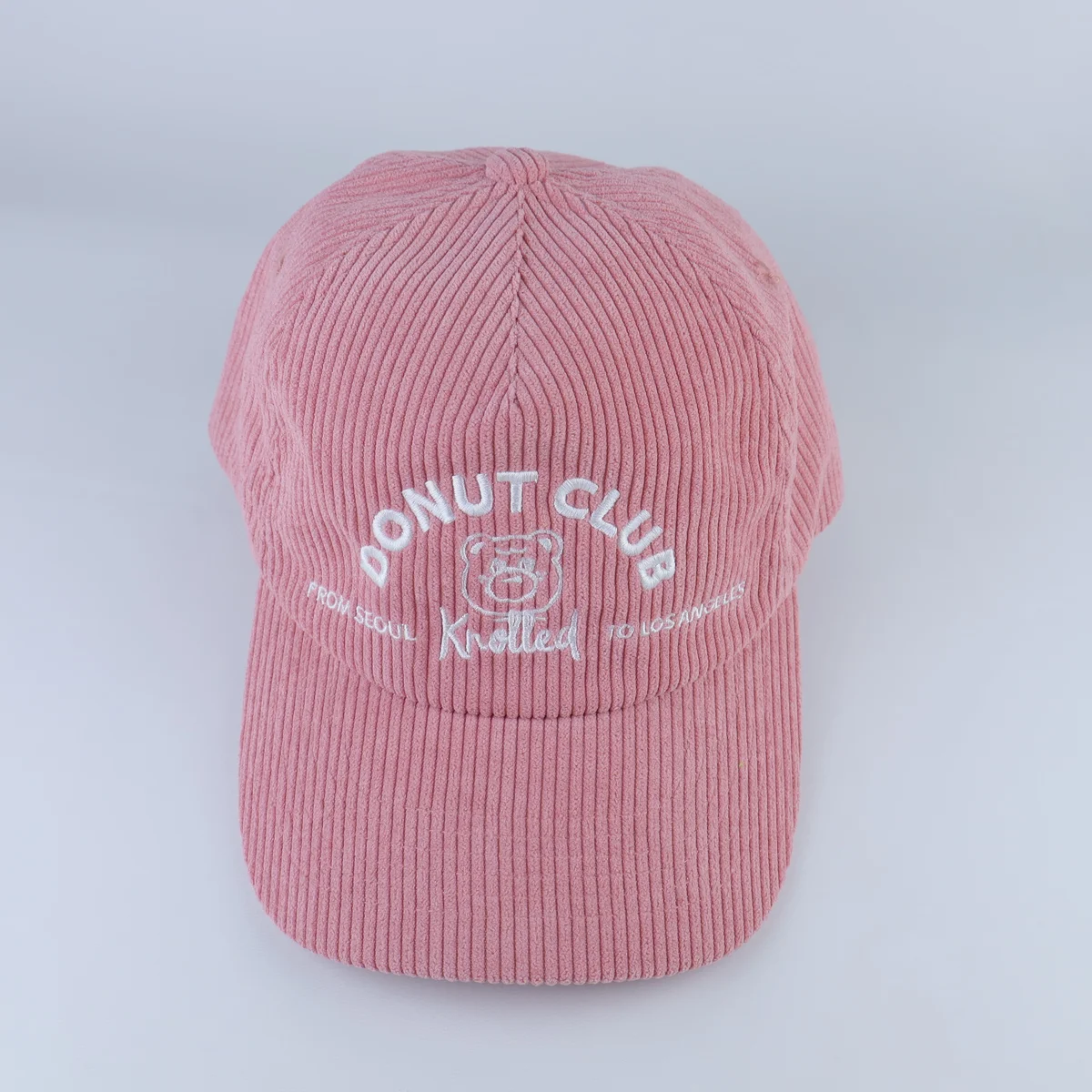 Pink corduroy baseball cap with white embroidered front lettering