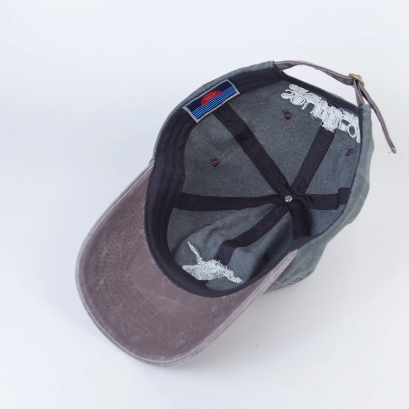 Inside view of the washed green bird-embroidered cap, showing seam tape, stitching and the back strap
