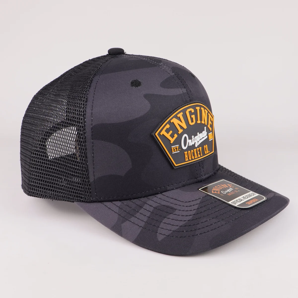 Side view of black patch trucker cap showing dark camouflage panel and mesh back